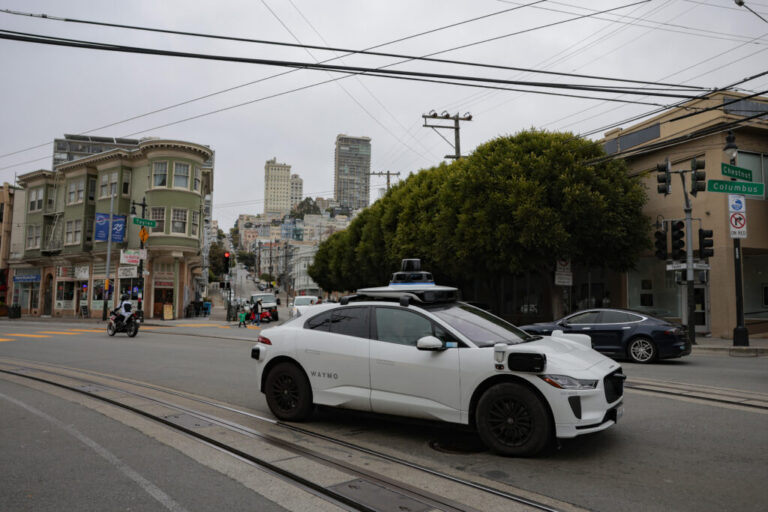A white Waymo robotaxi equipped with cameras on its sides and roof drives in San Francisco's North Beach neighborhood this week.