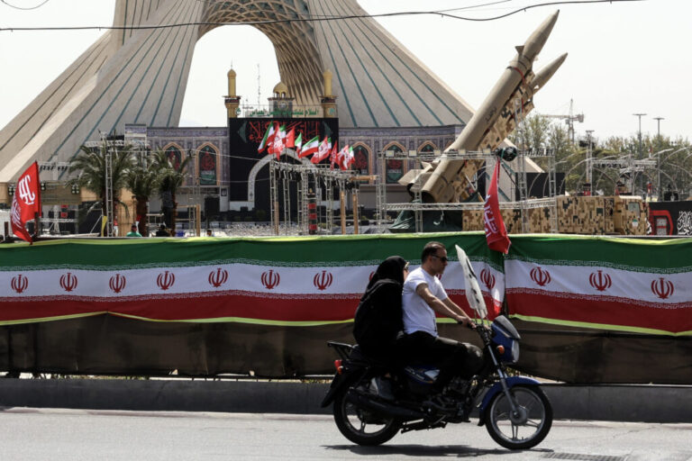 An Iranian couple rides past Iranian-made Zolfaghar missiles displayed at Azadi Square in Tehran on Friday. Iran's army said it carried out drone strikes against several U.S. military facilities and bases in Bahrain and Jordan in retaliation for the latest U.S. attacks against Iran.