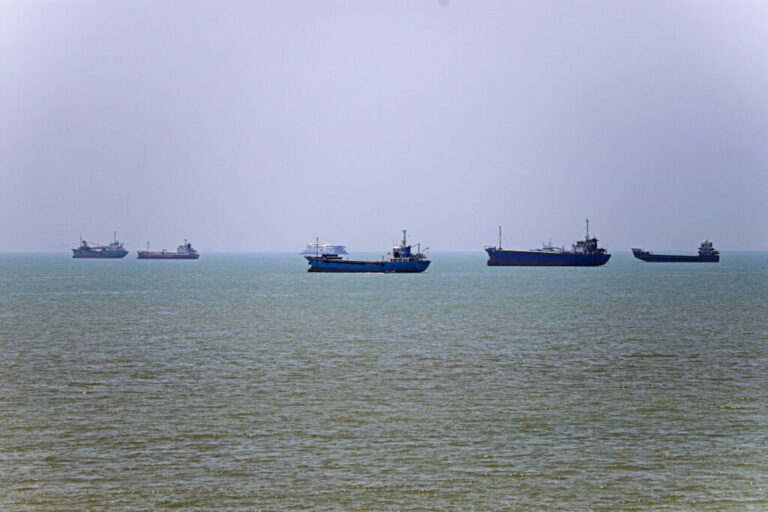 In this photo, six vessels float on the water, anchored along the Strait of Hormuz.