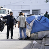 A Miami police officer talks with a homeless person, prior to a cleaning of the street in 2021. Starting October 1st, a new law will ban Florida's homeless from sleeping in public spaces.