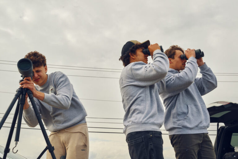 Teammates Otys Train, 16, (left), Zade Pacetti, 16, and Jack Trojan, 17, look through a scope and binoculars as they aim to identify as many bird species as possible during the World Series of Birding at Malibu Beach Wildlife Management Area in New Jersey.