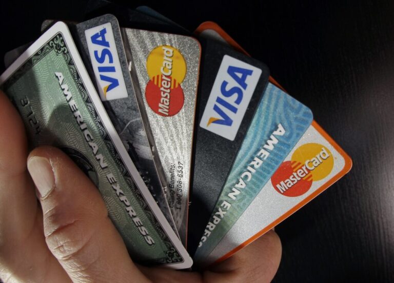 A close-up shows a hand holding various credit cards splayed out.