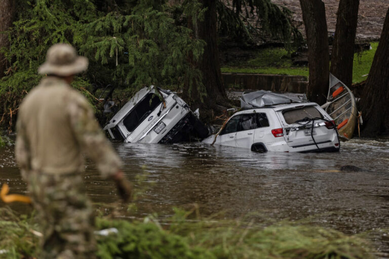 Search and rescue workers look through submerged vehicles.