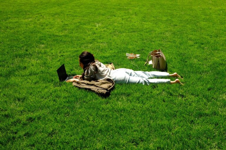 A woman uses a laptop as she lies on the grass in a park in the Manhattan borough of New York City on April 24, 2026.