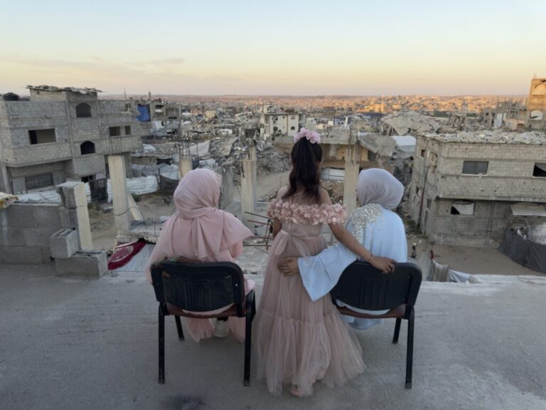 Three sisters sit looking out over a sea of debris as the sun sets in northern Gaza's militarized orange zone of Beit Lahia, on May 31.