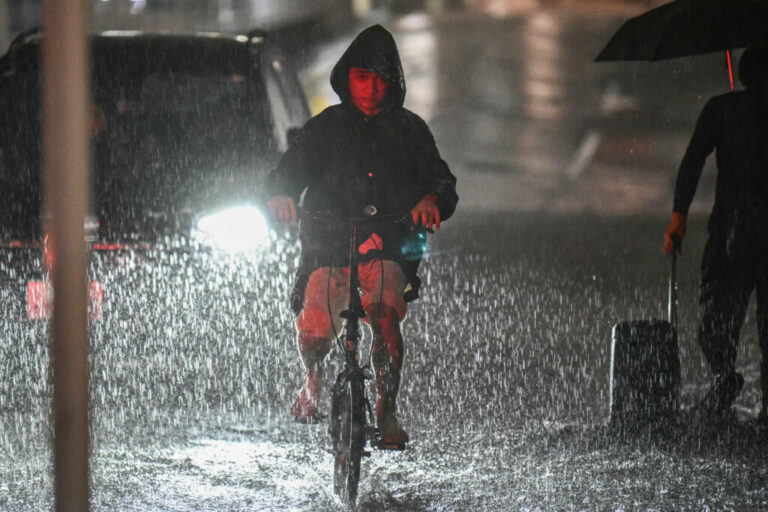 A man rides his bike along a flooded road near Chiba metro station in Chiba, Japan, on Aug. 13, 2026, as heavy rain swept through the area. Torrential rain pummeled eastern Japan, triggering landslides and power outages, and prompting the weather authority to issue its highest-level heavy rain warning for the region for the first time.