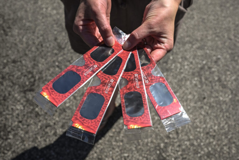 A member of the public shows the four pairs of solar eclipse glasses they bought from a stall on Custom House Quay,in Falmouth, England.