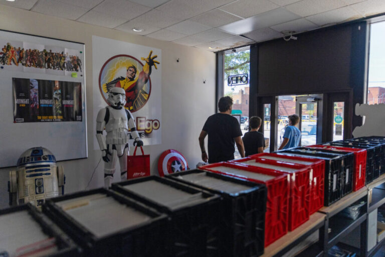 A man and two boys walk by lifesize models of R2-D2 and a Stormtrooper from Star Wars as they exit the store.