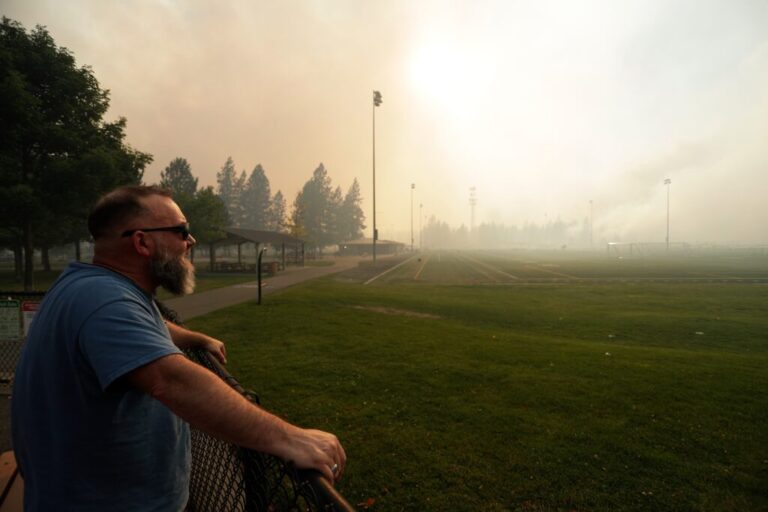 Andrew Rowley watches Old Trails Fire from Dwight Merkel Sports Complex after evacuating, on Aug. 1, 2026, in Spokane, Wash.