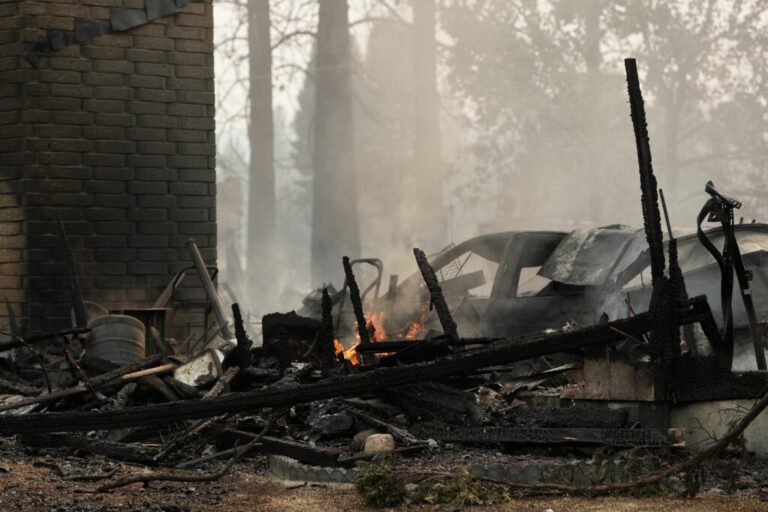 A house on N. Victor St. and W. Lyons Ave. burned by a wildfire smolders on Aug. 2, 2026, in Spokane, Wash.