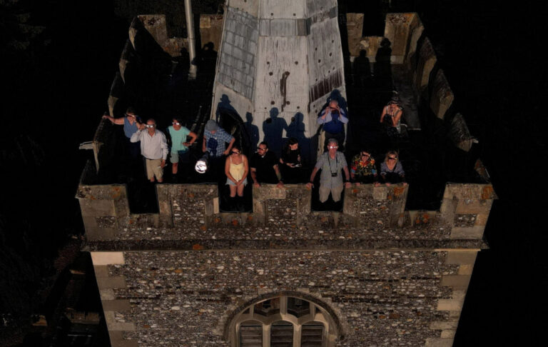 A drone picture of people wearing special protective glasses to observe a partial solar eclipse at the top of St Mary’s Church bell tower in Rickmansworth, Britain.