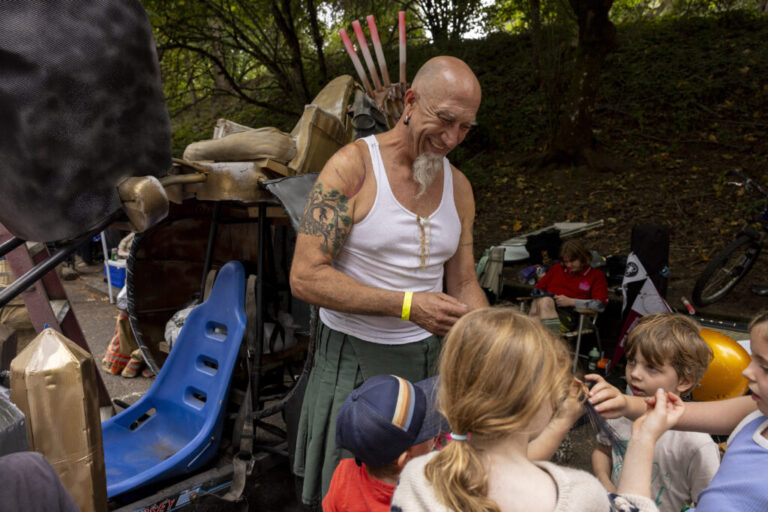 John Nurse speaks to children about his soapbox car and allows them to sit on the vehicle between races at the Portland Adult Soapbox Derby.