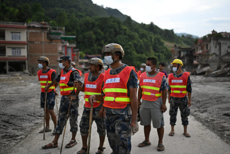 Rescue team personnel search through debris and mud covering an area following flash floods in DeviGhat village, Nepal.