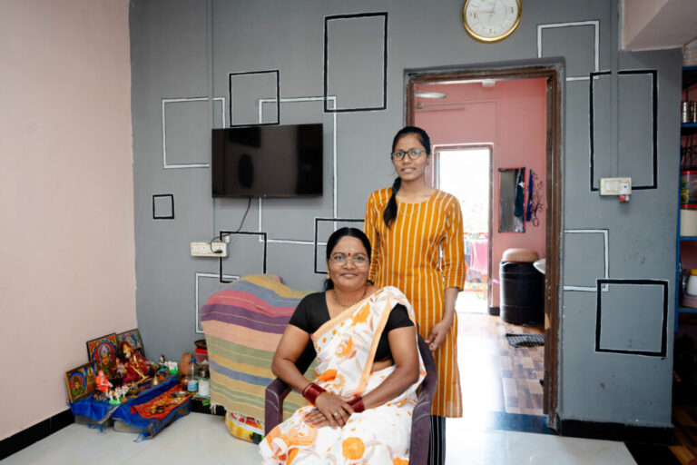 Savitha Yadava and her daughter 42, Poonam 19 pose in their living room, adjacent to a kitchen and the bedroom behind them. There's a small shrine in one corner. Moving into their new home helped the children secure good grades and well-paying jobs. Decorating her home has now become a passion she says.