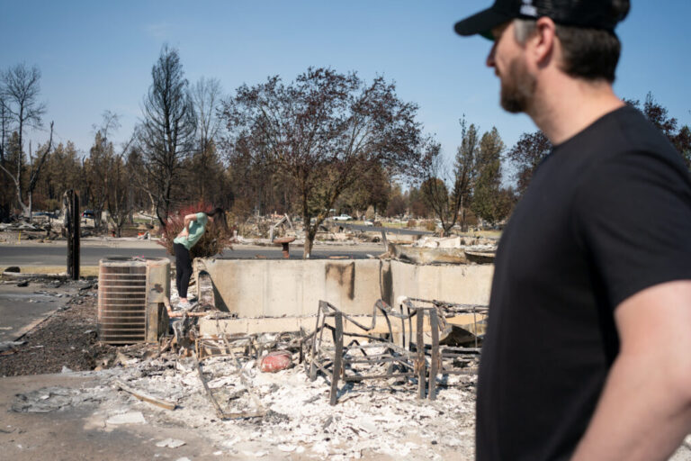 Melissa and Chris Matthews examine the remains of their family home in Spokane on August 14, 2026.