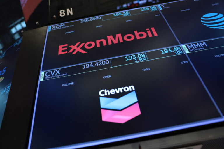 The logos for ExxonMobil and Chevron appear on display screens on the floor of the New York Stock Exchange during morning trading on July 24.