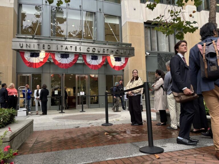 People line up outside the Oakland, California federal courthouse ahead of opening arguments in the trial that four state attorneys general are bringing against Meta Platforms, Inc.