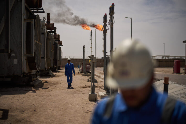 Workers walk in the Zubair oil field, whose operations have being reduced since the start of the Iran war, near Basra, Iraq, March 28.