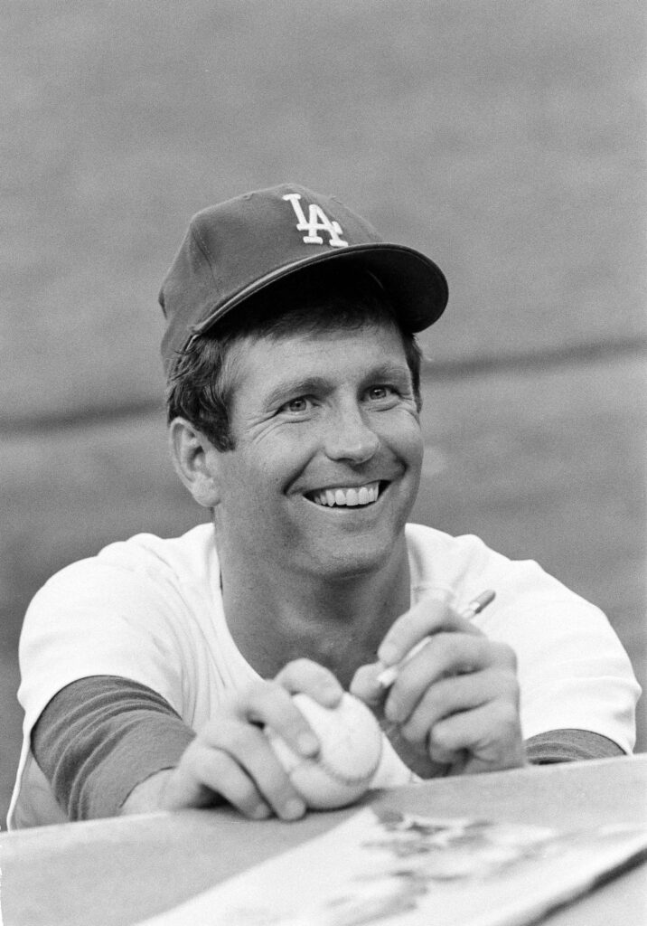 Lefthander Tommy John of the Los Angeles Dodgers signs an autograph before a game on Aug. 12, 1977.