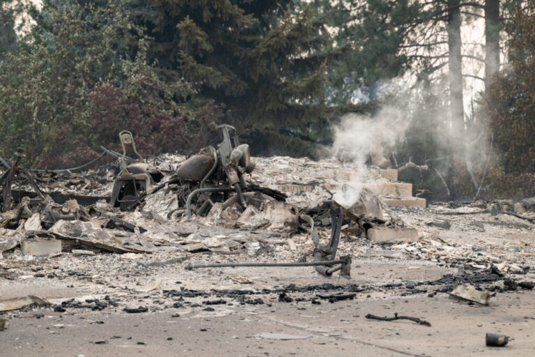 A burned motorcycle sits in the ashes of burned out residential home in the Balboa neighborhood of Spokane, Wash., on August 2, 2026.