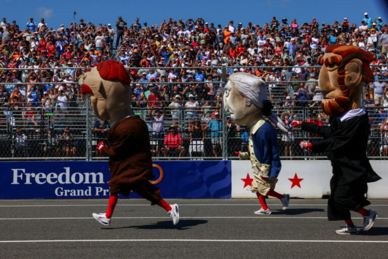 People in costumes appear on the racetrack ahead of the Freedom 250 Grand Prix IndyCar series race.