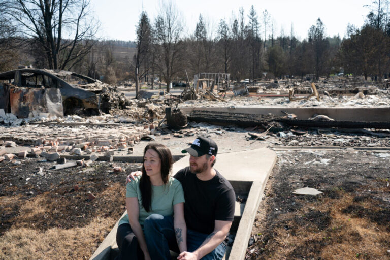 Melissa and Christopher Matthews in front of the remains of their home in Spokane on August 14, 2026. The Spokane Complex fires have caused over 900 structures to burn down.