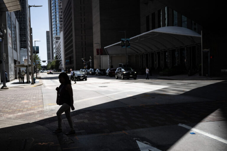 A woman walks in the shade in downtown Houston, Texas in late July 30 during a regional heat wave.
