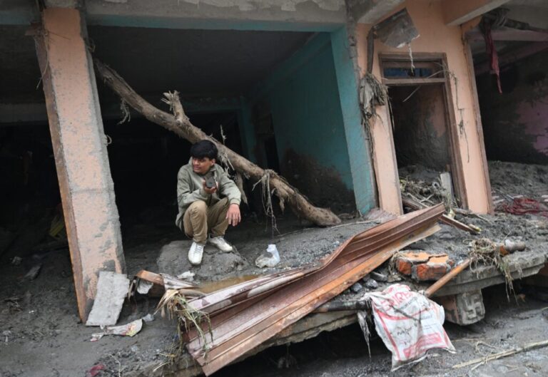 A man sits amidst debris of a house deluged in sludge following flash floods at Devighat in Nepal's Nuwakot district.