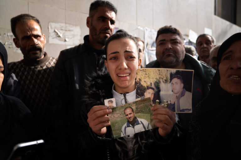 Sarah Abdel Hamid Al-A'ami holds photos of her 4 brothers who were all accused of terrorism under the Assad regime, and though she came to search posters of dead bodies, she still hasn't found any signs of them.