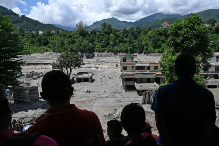People watch from a rooftop as houses lay deluged in sludge after flash floods at Trishuli in Nepal's Nuwakot district.