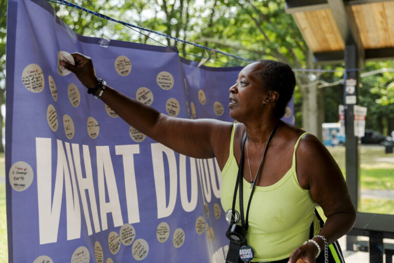 Rose Edwards, 66, puts a sticker with her hopes for the future on a banner at a community meetup event for Dr. Abdul El-Sayed in Rouge Park on July 26, 2026 in Detroit, Mich. “You have to get involved in the community, you can’t complain and then not get involved. I love him and he has my vote and I can't wait to see what he does when he gets to Washington,” Edwards said.