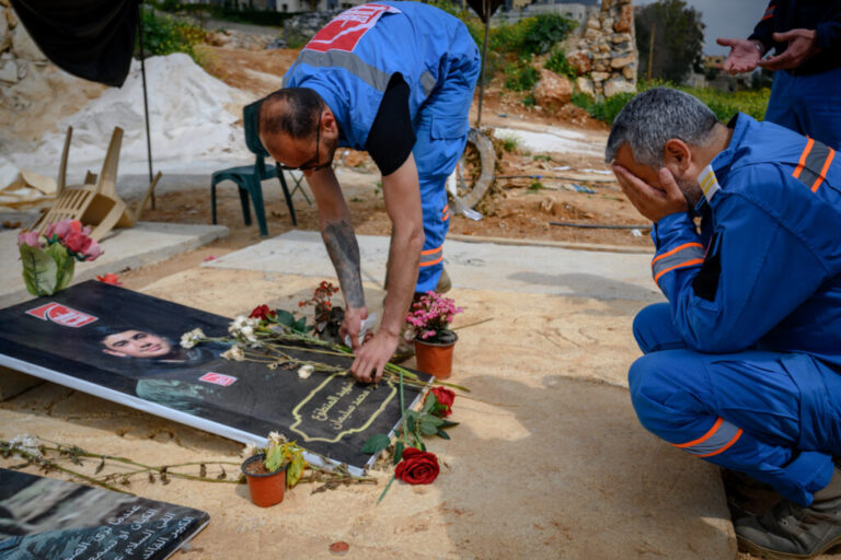 Mohammed Suleiman (right), a veteran Lebanese paramedic and co-founder of the Nabatiyeh Ambulance Service, mourns at the flower-festooned grave of his 16-year-old son Joud, on April 28, in Nabatiyeh, Lebanon. Joud was a rescue team assistant who was killed by an Israeli drone while riding a motorcycle with team paramedic Ali Jaber, both men in uniform, on March 24.