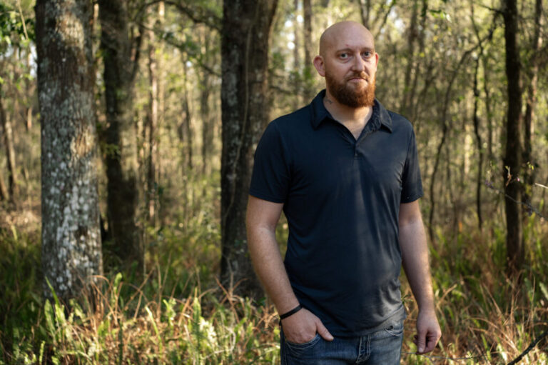 Wade Hanicker stands in a wooded area at his home in Brooksville, Fla.