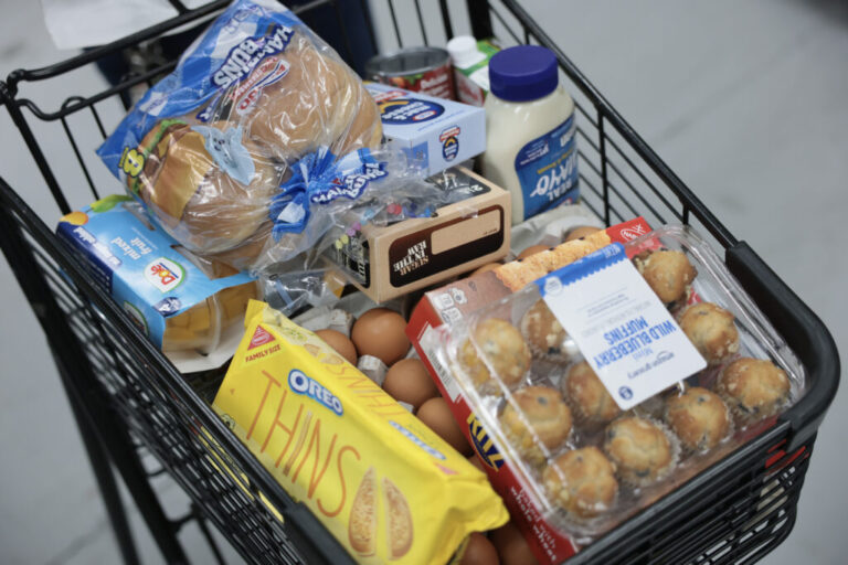 A grocery cart is full of food items.