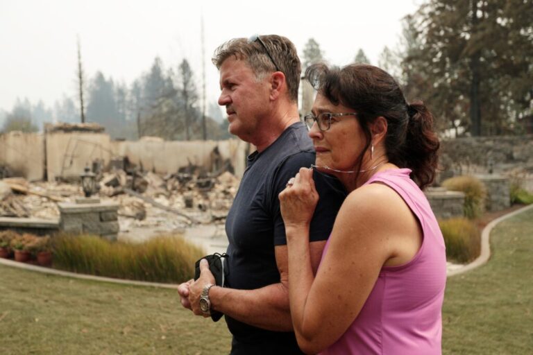 Dan Munson and his wife Suzi Munson stand in the backyard of their house on W. TIffany Ave. which burned in a wildfire, on Aug. 2, 2026, in Spokane, Wash.