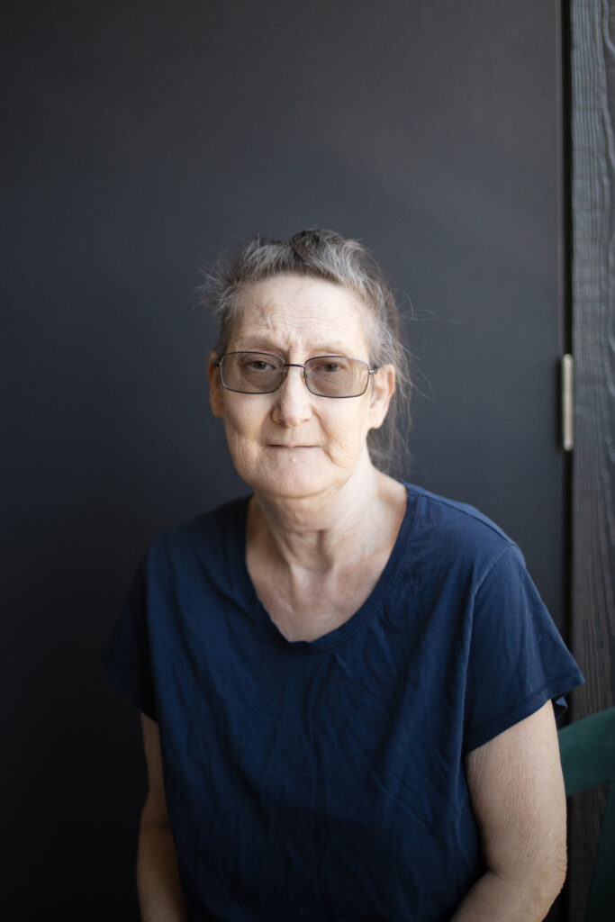 Debbie Willson is wearing a dark T-shirt and glasses.