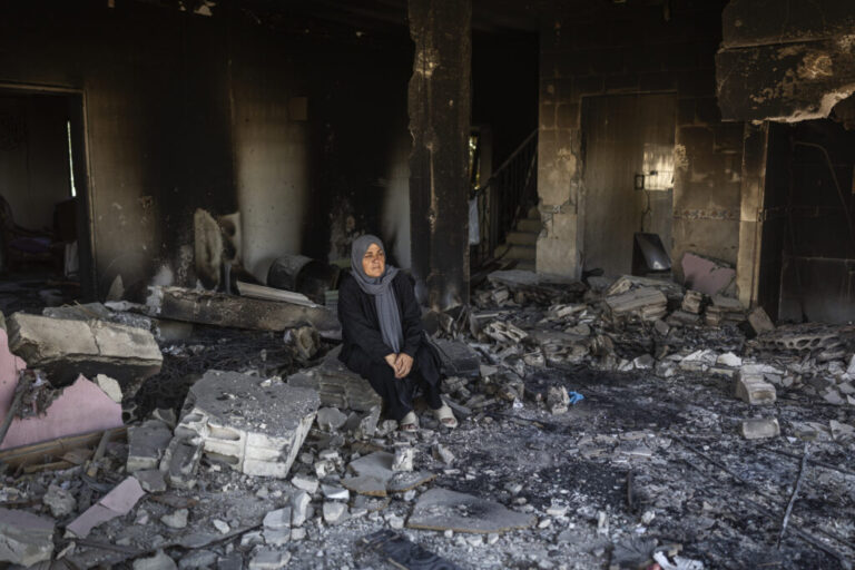 Ihsan Yaghi stands inside her heavily damaged home. She was displaced to Beirut's southern suburbs but returned to her village of Zawtar al-Gharbieh every day. She has six daughters, and her husband is retired.