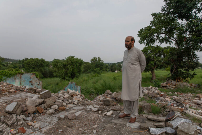 Tanvir Hussain, a lawyer and resident of Nurpur Shahan, stands near the demolished home of his friend on August 19, 2026 in Islamabad, Pakistan. He says decades-old compensation for land that was seized by the government in his area was never properly carried out.