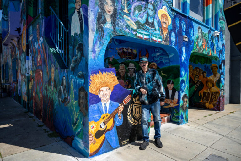 Richard Segovia stands in front of his house on 25th and York streets, known as the Latin Rock House, in San Francisco on April 7, 2026. The home is covered in a large mural honoring dozens of musicians tied to the Mission District’s Latin rock scene, which Segovia has helped preserve for decades.