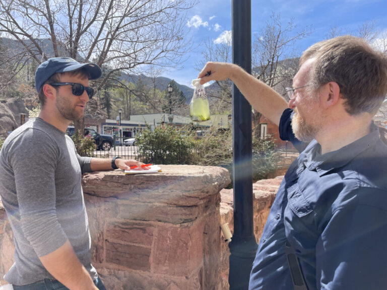 James Henriksen, an environmental microbiologist at Colorado State University, holds up a water sample for Braden Tierney, a microbiologist at Harvard Medical School. The bag is teeming with microbes, a group of organisms that these researchers hope may hold the solutions to some of humanity’s big problems.