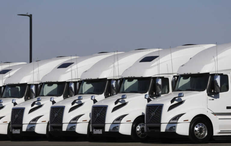 A line of white semi-trucks parked side by side.