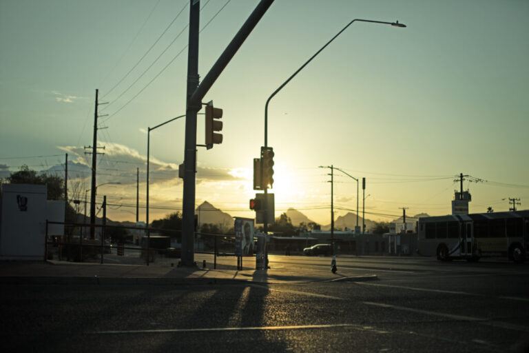 The sun shines behind a streetlight at an intersection in Tucson, Arizona.