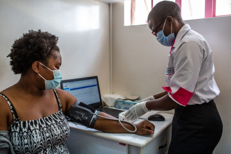 A health worker measures the blood pressure of a woman at Penda Health Clinic Umoja II in Nairobi, Kenya, where researchers have tested an AI tool that can check out the notes taken by clinicians.
