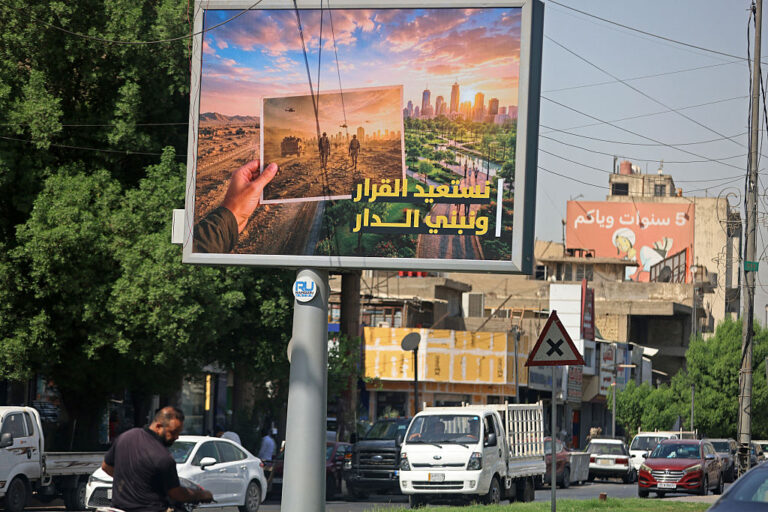 Vehicles drive past a billboard carrying the Arabic slogan 'Reclaiming the decision and building the home', at the Saadoun Square in Baghdad on September 29, 2026.