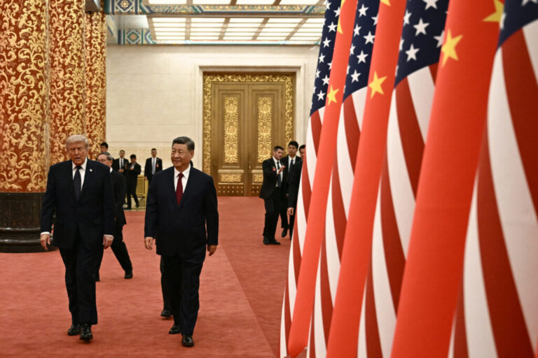 China's President Xi Jinping and President Trump walk past a line of alternating U.S. and Chinese flags.