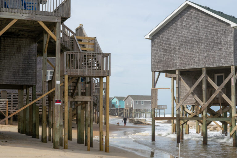 Ocean waves wash under beachfront houses that stand on wooden stilts in Buxton, North Carolina, in May.