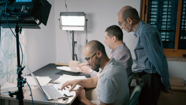 Yazeed Abu Khdeir (left) and Mahmoud Muna work to digitize papers, as Raja Shehadeh (standing) looks on August 2025.