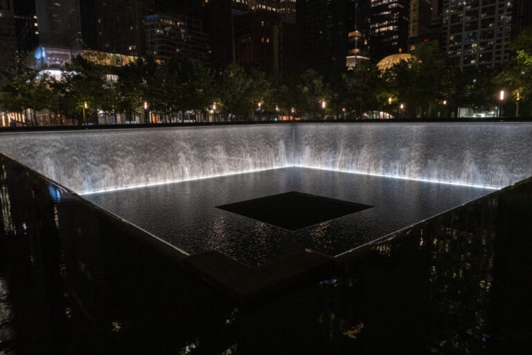 This photo, taken after dark, shows one of the twin reflecting pools at the 9/11 Memorial in New York City on September 2, 2026. The square pool sits in the footprint of one of the original World Trade Center twin towers. Water falls down the inner walls of the pool.