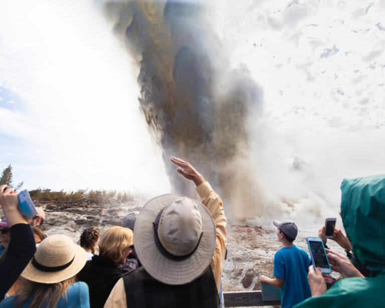 Wyoming, USA - A crowd of people witness the rare eruption of Steamboat Geyser, which can rise hundreds of feet into the air.