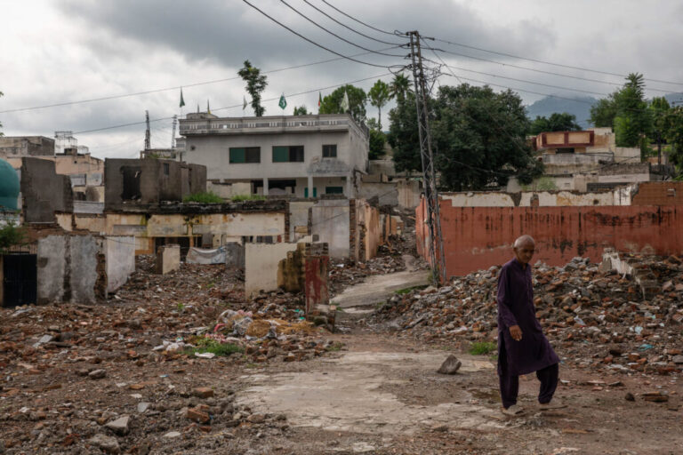 A man walks in front of demolished buildings near Bari Imam on August 20, 2026 in Islamabad, Pakistan.